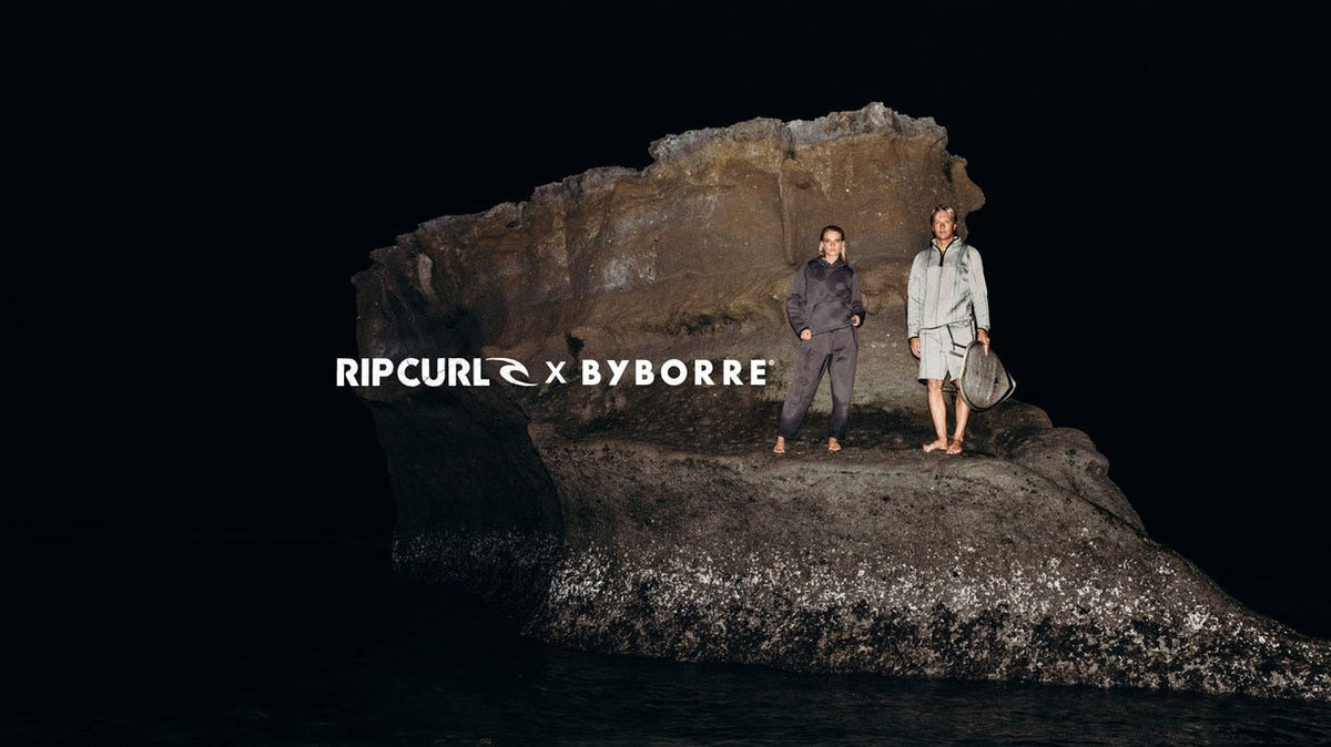 Surfers on a rock with the white text overlay