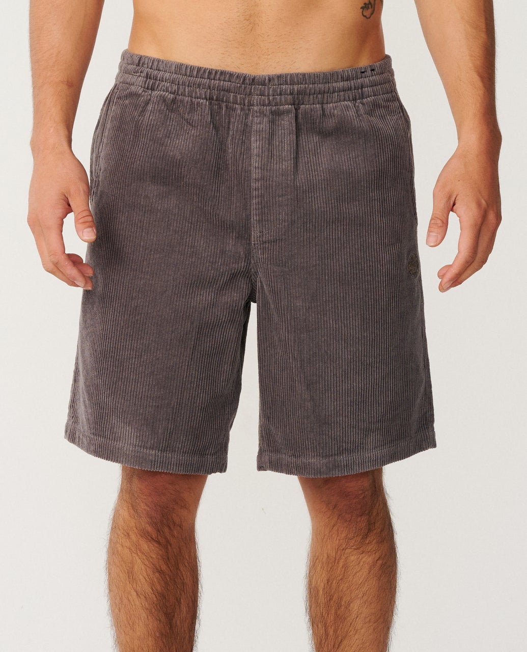 A person wearing gray corduroy shorts, standing with arms at their sides, against a plain background.