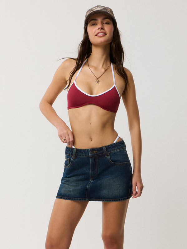 Woman wearing a red bikini top and denim shorts on a plain background