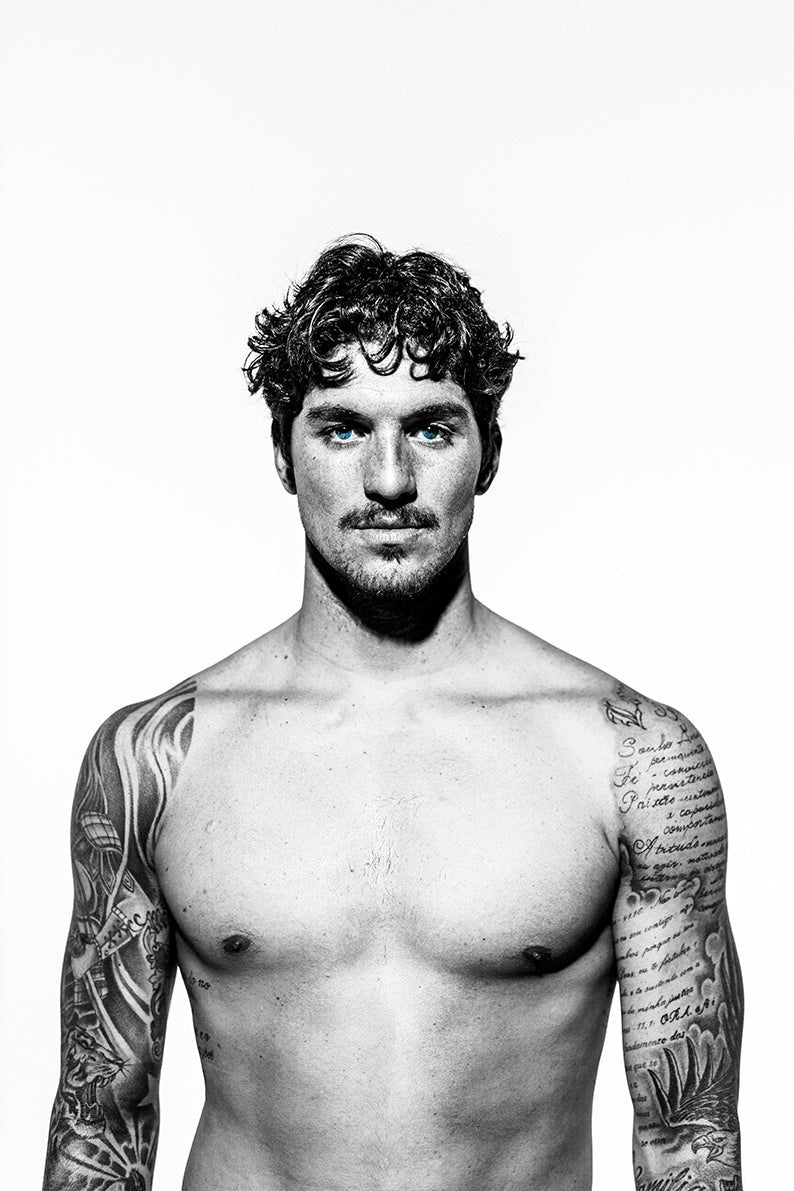Black and white portrait of a shirtless man with tattoos on a white background