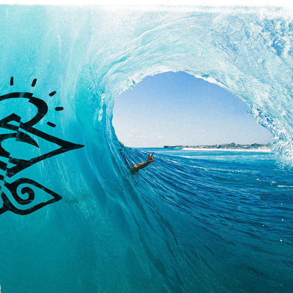Person surfing inside a large wave with a brand logo on the side.