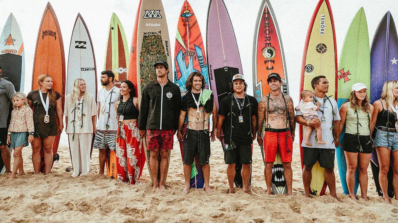 Group of people standing on a beach with colorful surfboards behind them