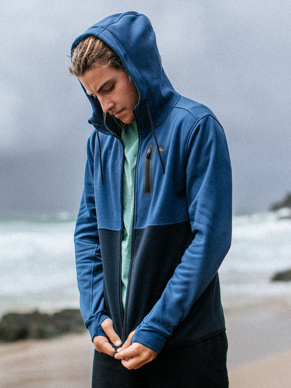 Person wearing a blue and black hoodie on a beach