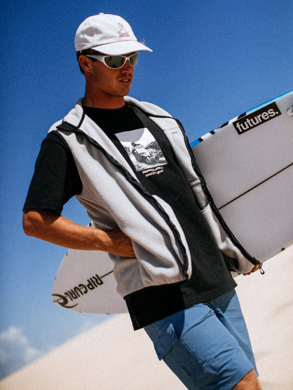 Man holding a surfboard with a clear blue sky background