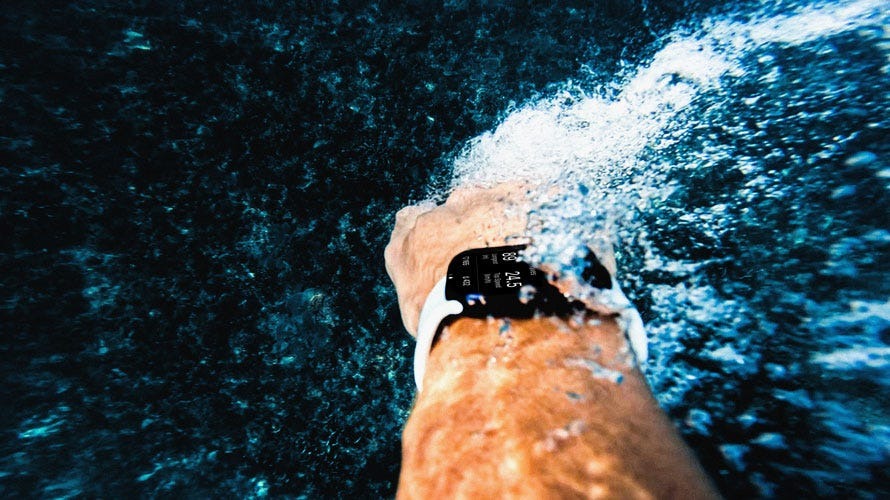Person swimming underwater with a smartwatch on wrist