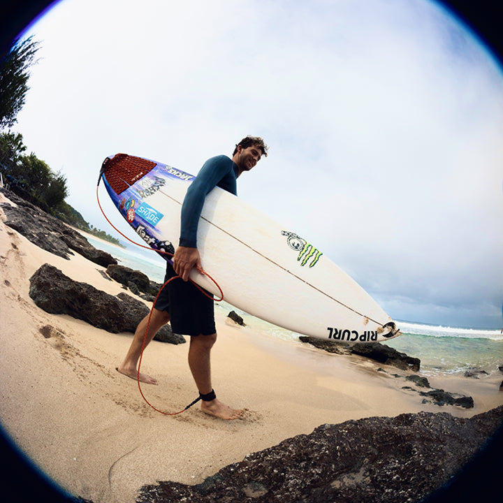 Person holding a surfboard and kite on a beach