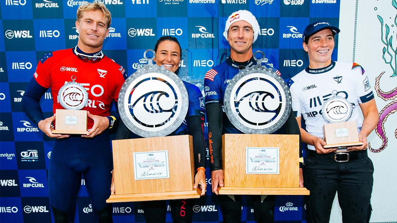 Four surfers holding awards in front of a branded backdrop