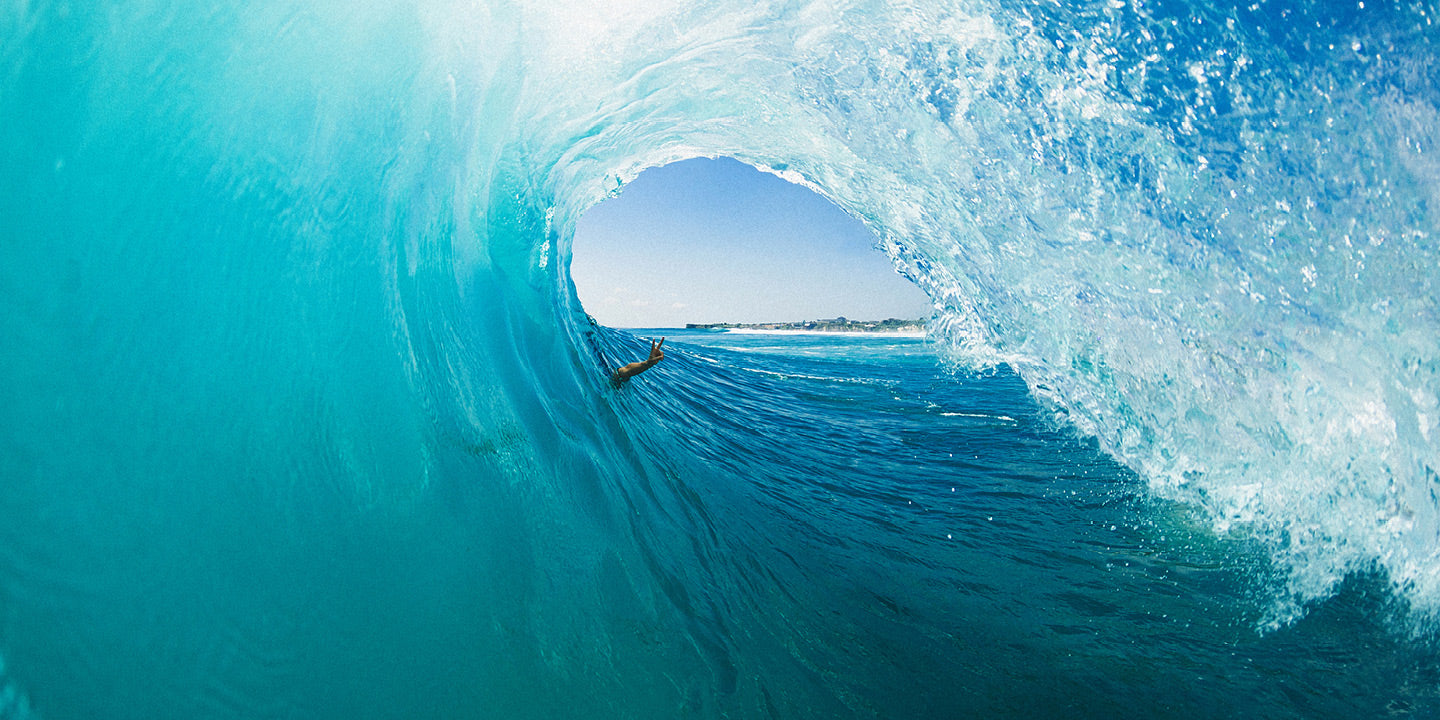 Surfer riding a large wave in crystal blue water