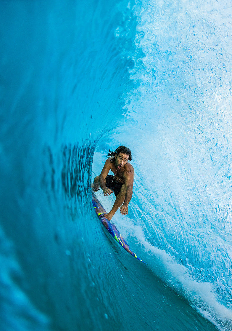 Person surfing inside a blue wave