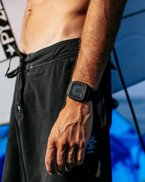 Person wearing a black smartwatch with a blurred background