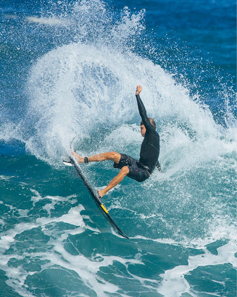 Surfer performing a trick on a wave with a blue ocean background