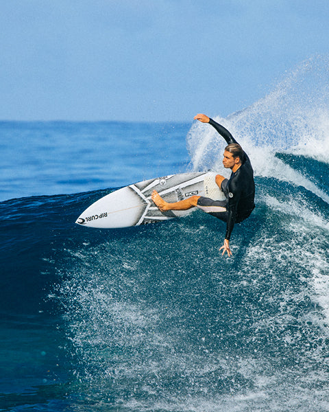 Person surfing on a wave with a clear blue sky