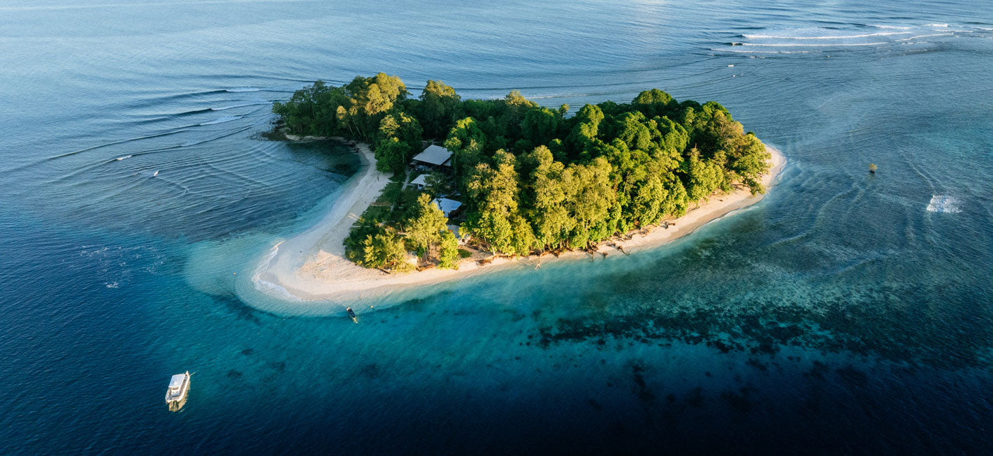 Island surrounded by clear blue water with a boat nearby
