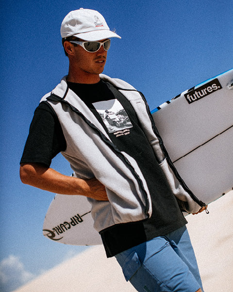 Person holding a surfboard with a clear blue sky background