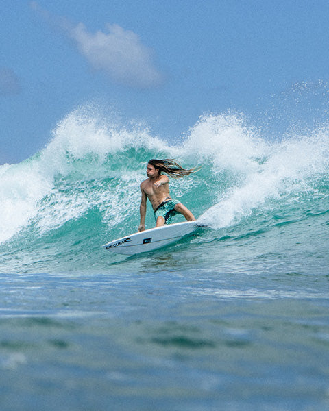 Person surfing on a wave with clear blue sky