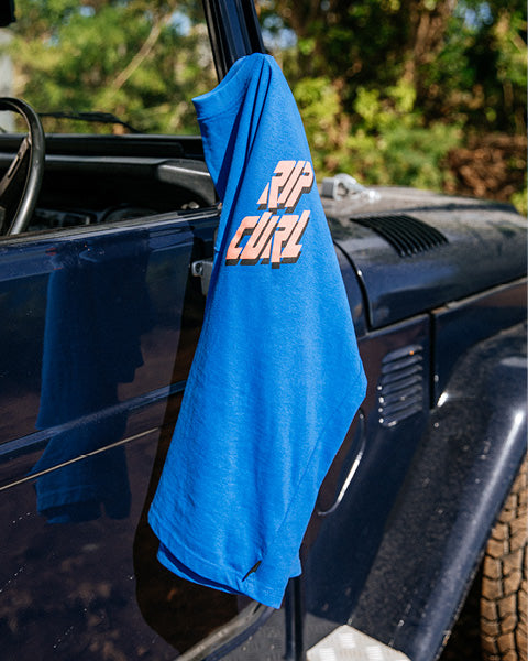 Blue t-shirt with 'Rip Curl' logo hanging on a car door