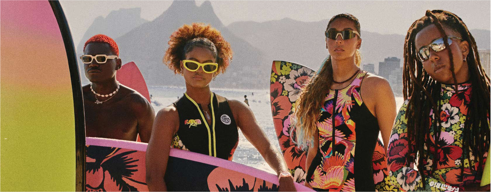 Four people with colorful surfboards against a mountainous background