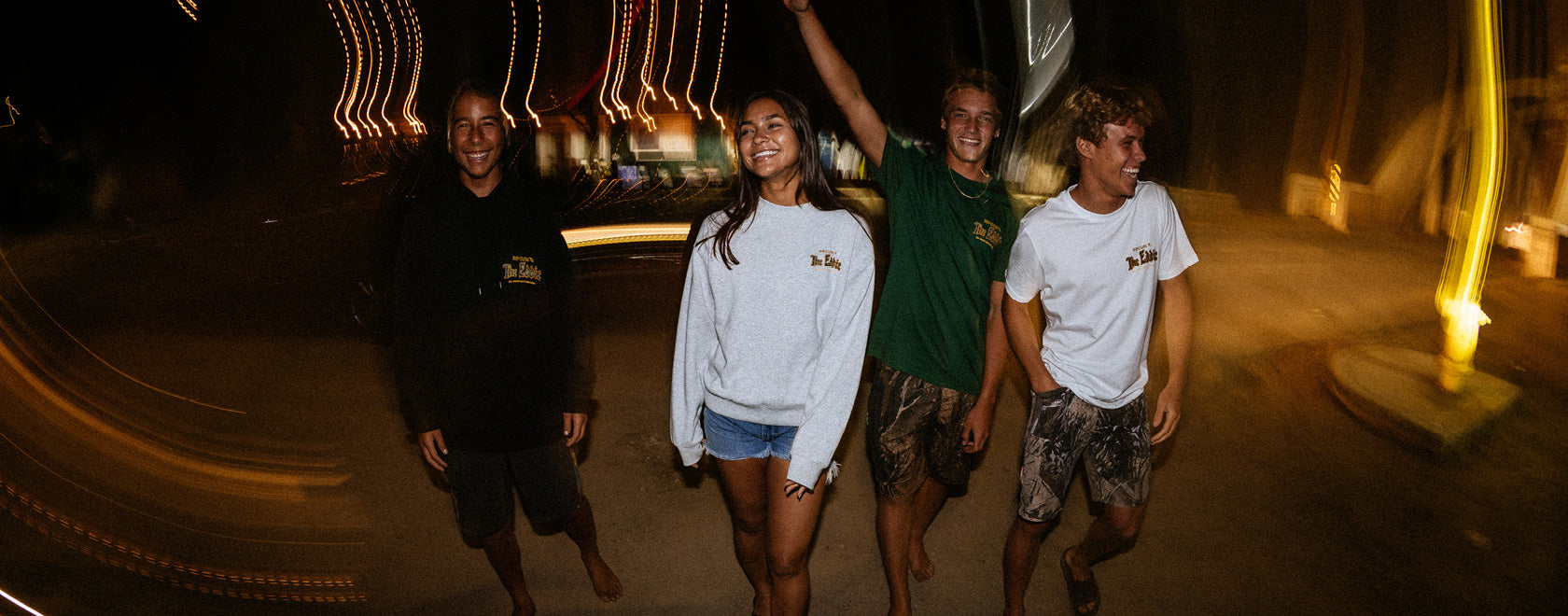 Four people standing together at night with lights in the background