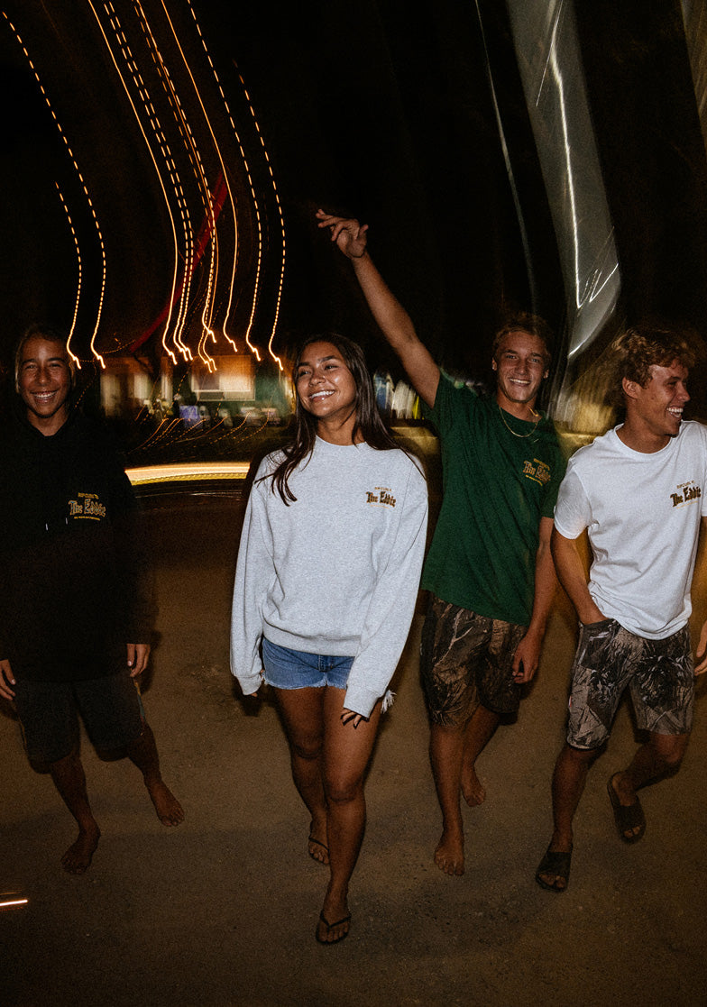 Four friends are walking together at night with lights in the background.