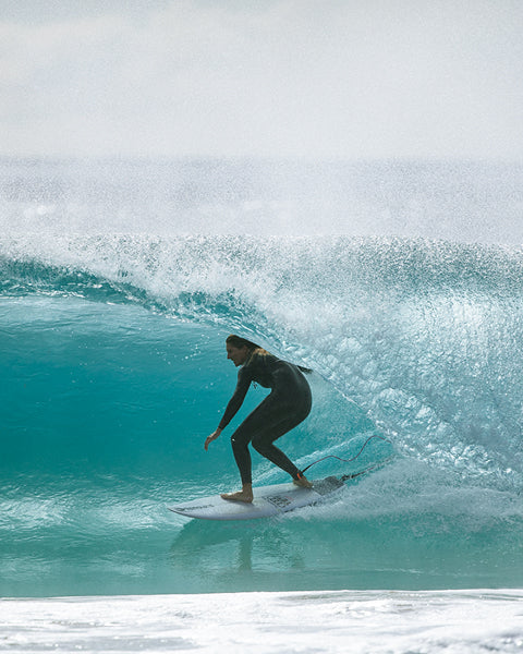 Person surfing on a large wave in clear blue water