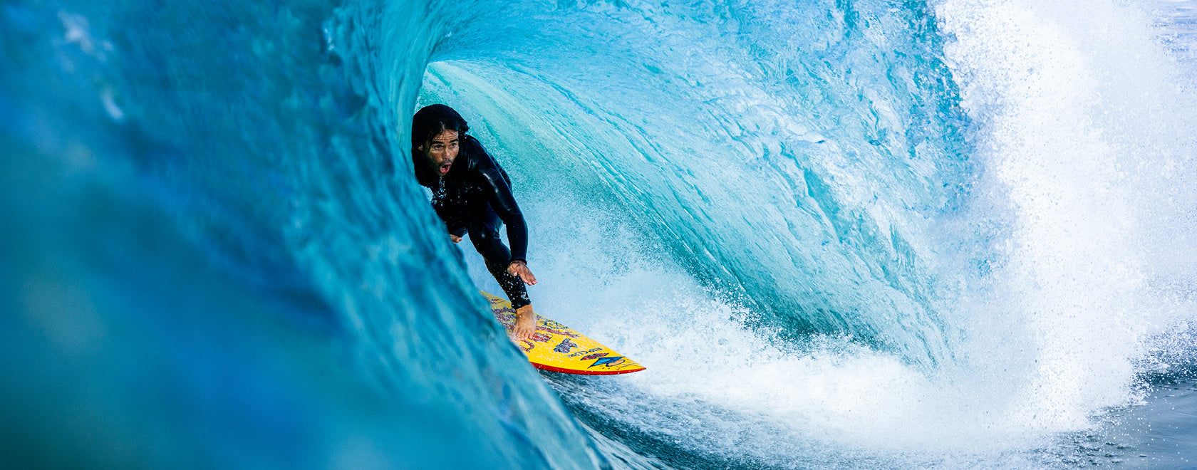 Person surfing on a yellow surfboard inside a blue wave.