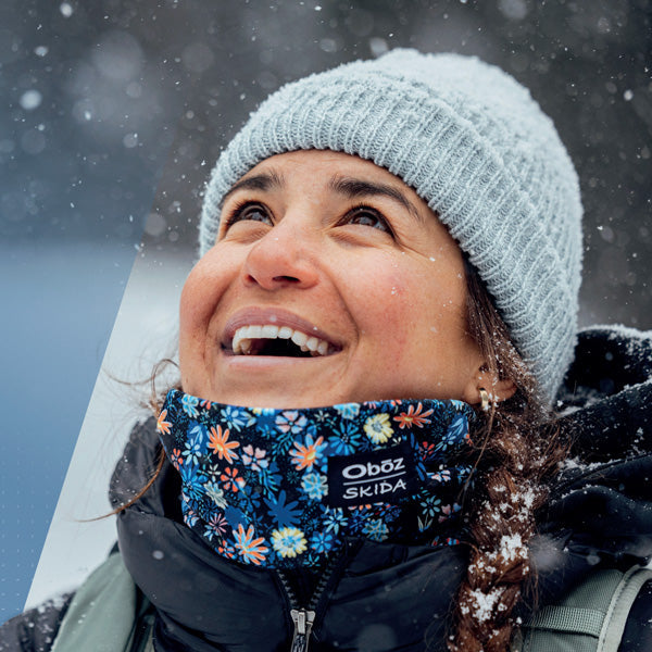 Person wearing a floral face mask with 'Oböz' branding in a snowy environment