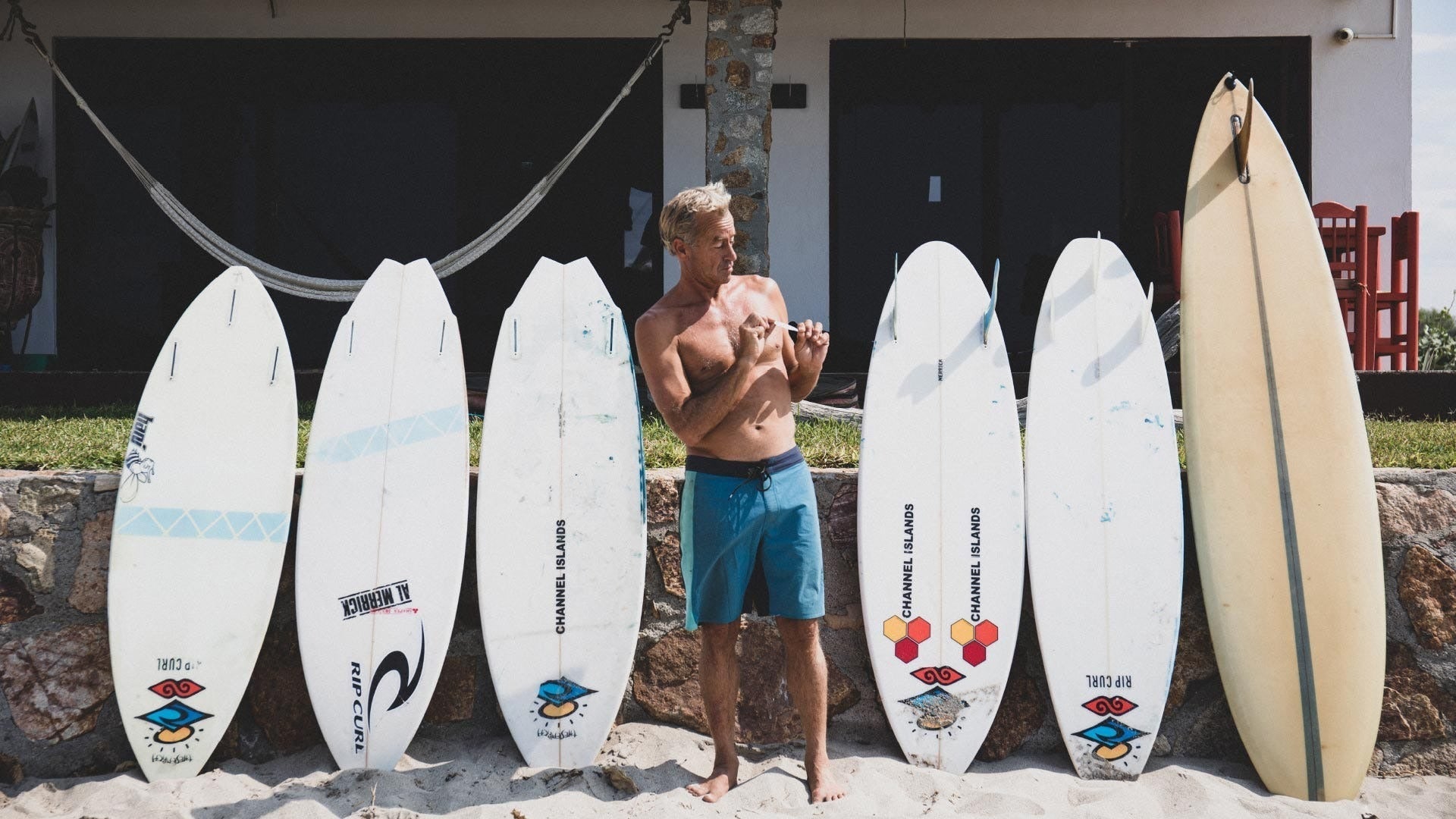 Man standing among surfboards with various designs on a stone surface.