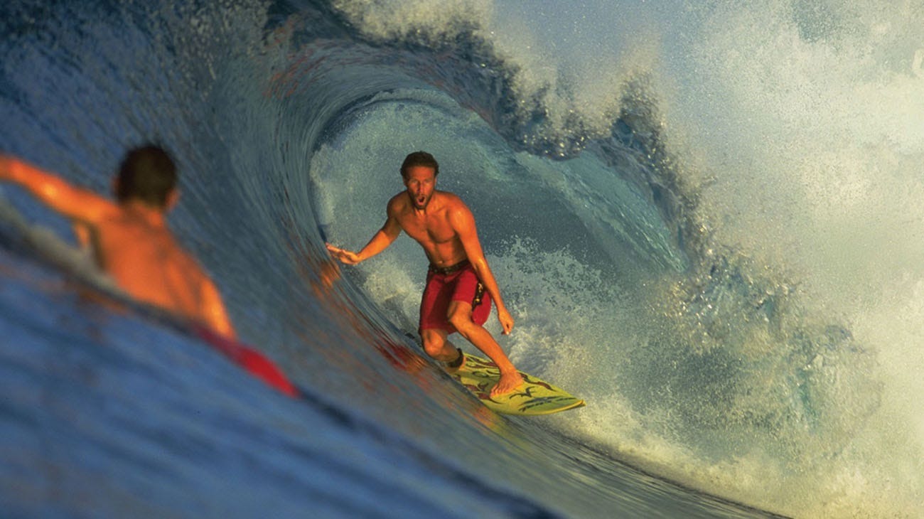 Two surfers riding a wave in the ocean.
