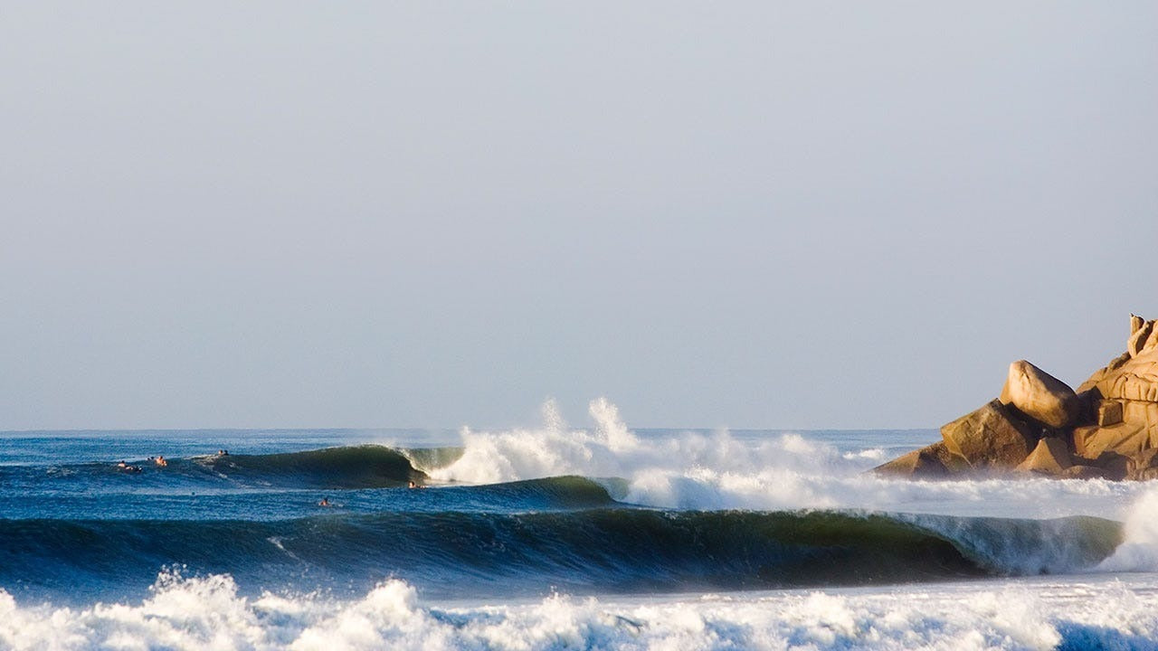 Ocean waves crashing against rocks with a clear sky