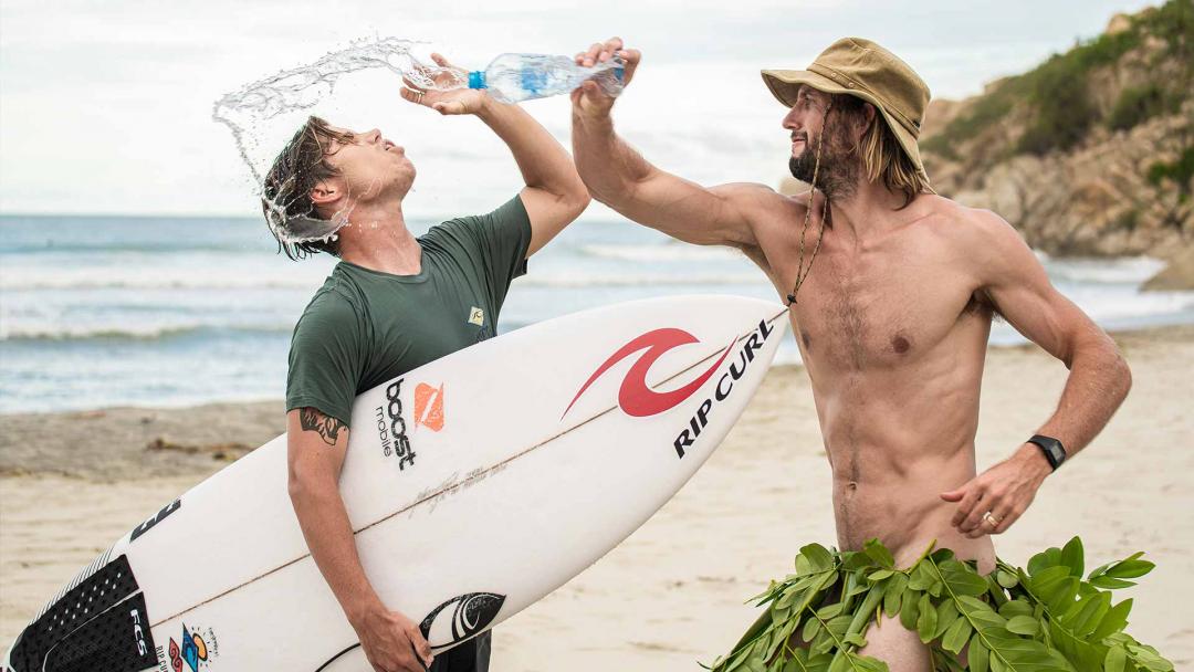 Owen Collects Plastic Bottles Along A Beach In Mexico In A Grass Skirt