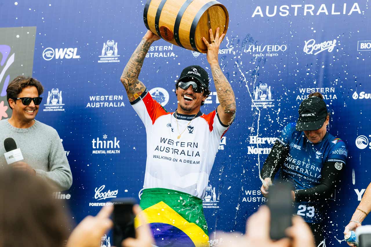 Gabriel Medina holding up his trophy being sprayed by champagne.