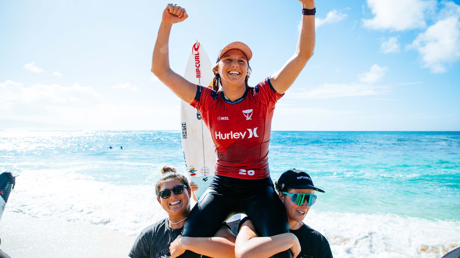 Molly Picklum being chaired up the beach by Brisa Hennessy and Tyler Wright