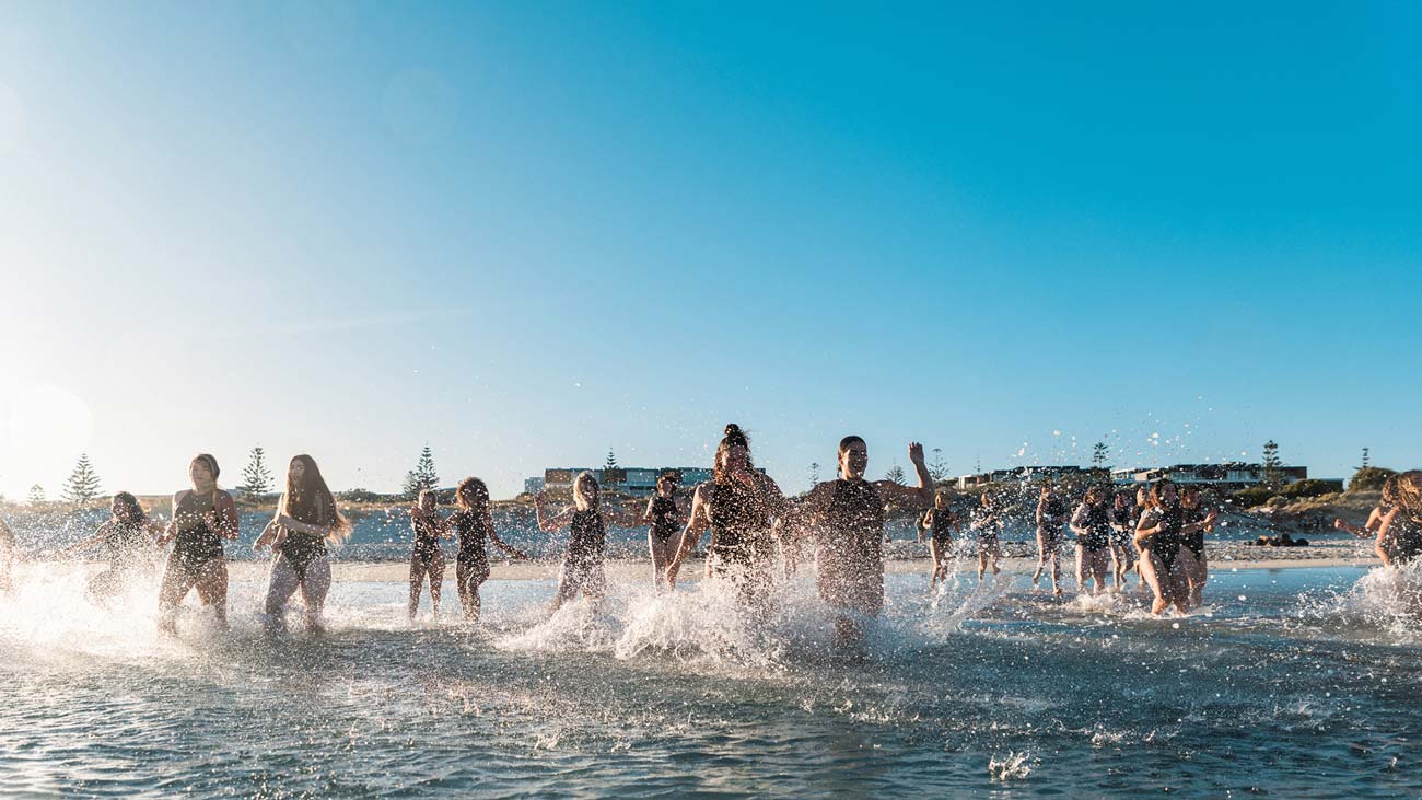 Group shot of the Sea Gals community group running into the ocean in Western Australia