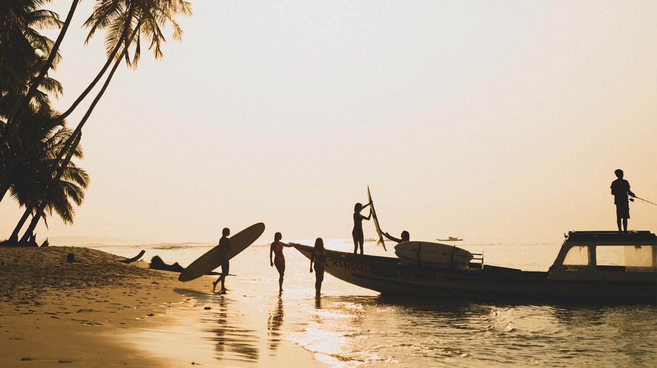 Silhouettes of the Rip Curl crew putting their gear onto a boat at sunset