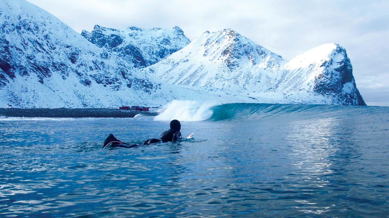 Mick Fanning paddling out surrounded by icebergs and snow capped mountains