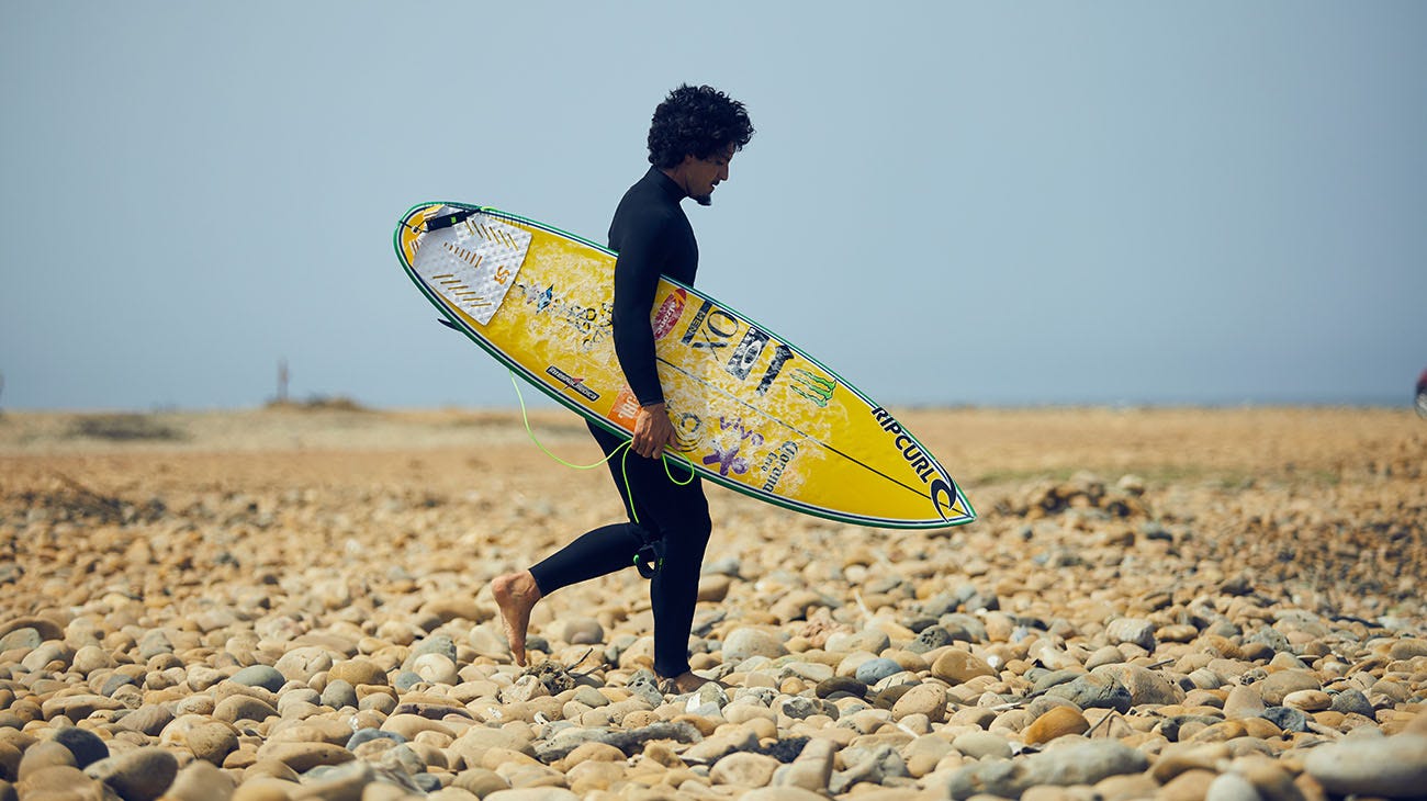 Gabriel Medina walking down the beach 