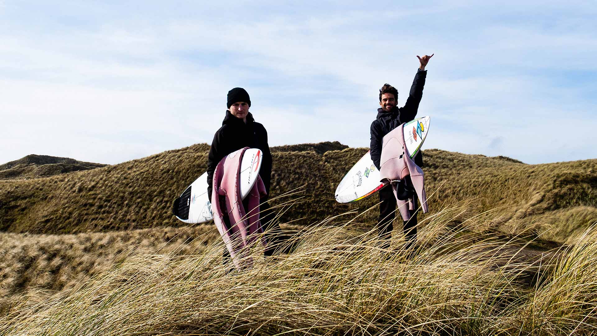 Mason Ho and friend in Scotland fields holidng surfboards