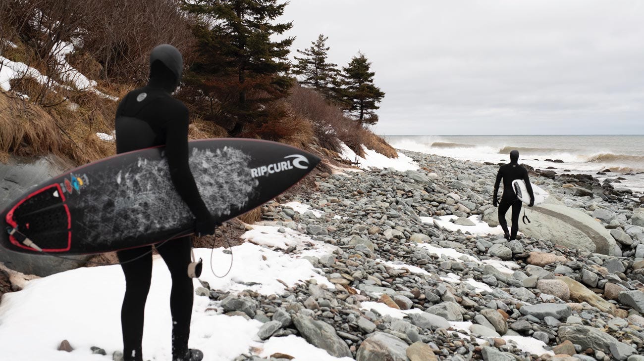 Rip Curl crew walking along a rocky beach in Nova Scotia, Canada