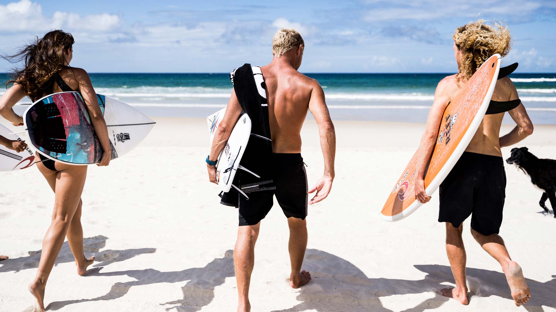 Mick Fanning running into the ocean with friends.