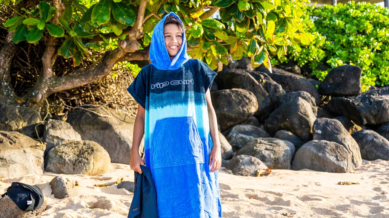 Rip Curl grom wearing a hooded towel on the beach in Hawaii