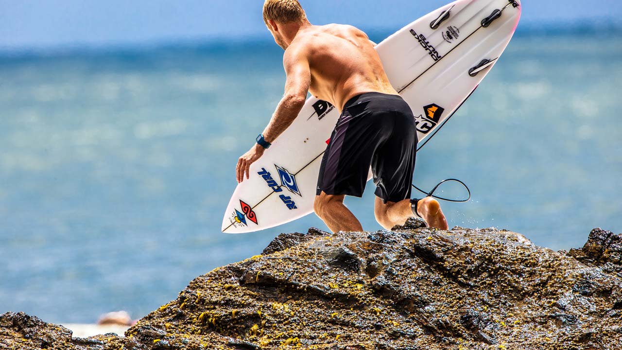 Mick Fanning jumping off the rocks at Snapper in Rip Curl boardshorts