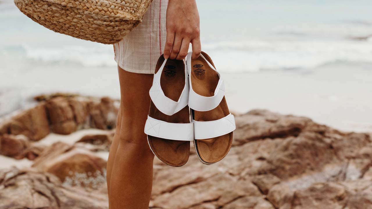 Model holding a pair of white Rip Curl sandals