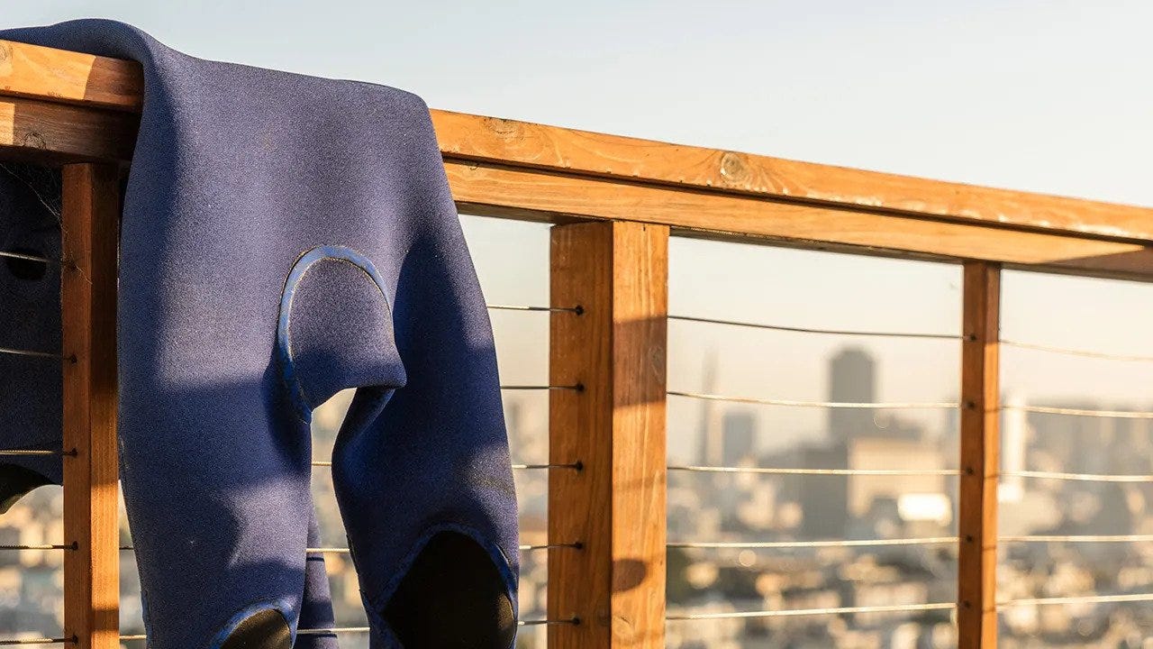 E-Bomb Rip Curl wetsuit hanging up on a wooden hand rail to dry after a surf.