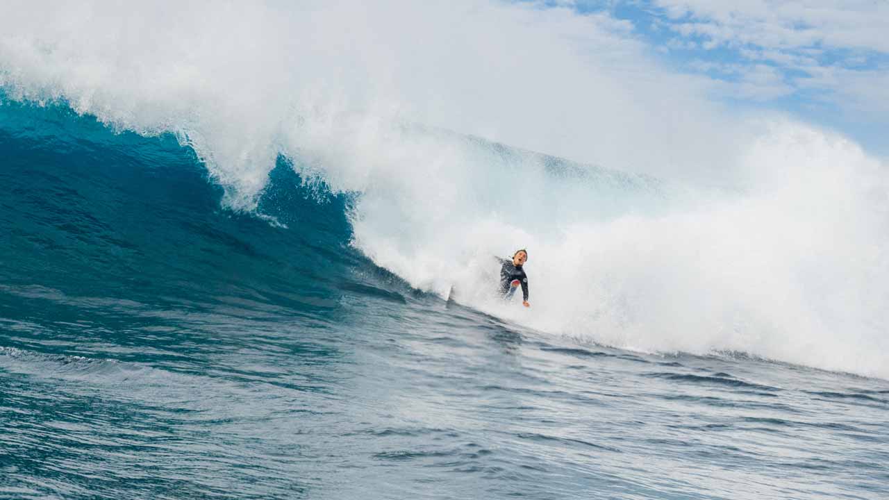 Mason Schremmer sitting on her board looking at a busy line up.