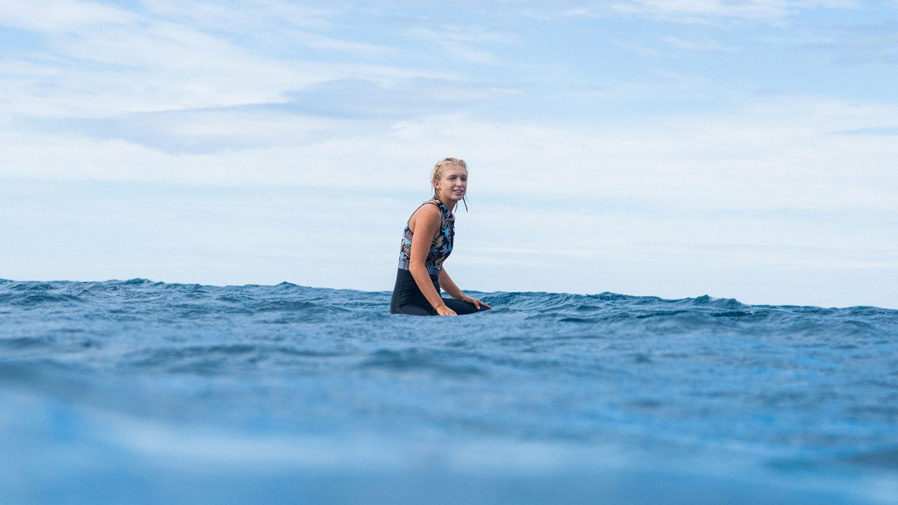Mason Schremmer sitting on her board in the ocean waiting for a wave.