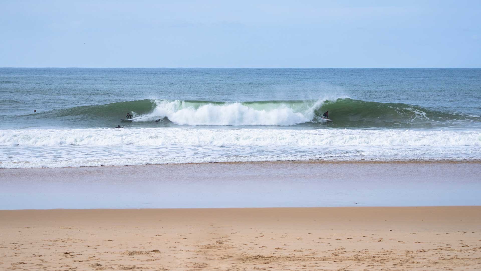 People surfing left and right on a wave in Panieche Portugal