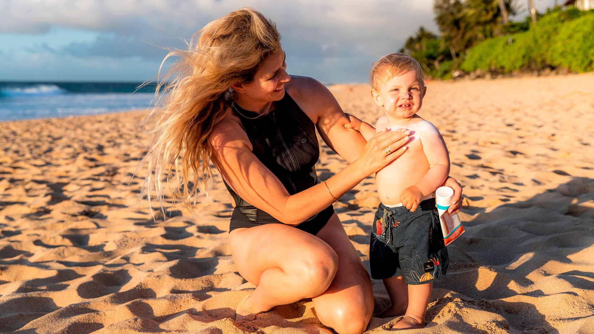 Rosy Hodge rubbing sunscreen into her son.