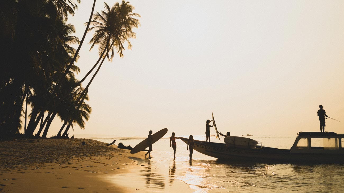 Silhouette of people putting gear onto a boat at sunset