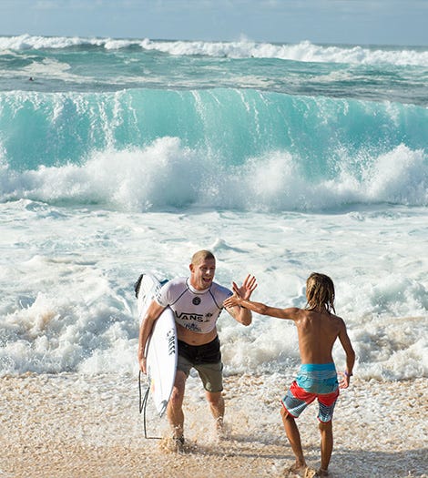 Mick Fanning high fives a fan on the beach