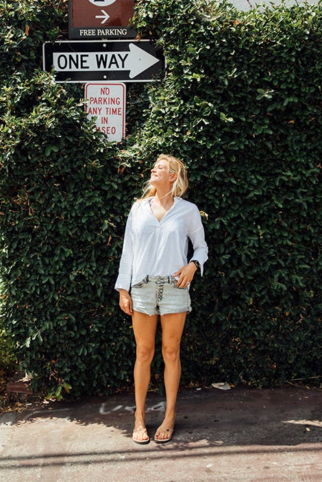 Candid image of Rosy Hodge in front of a green hedge